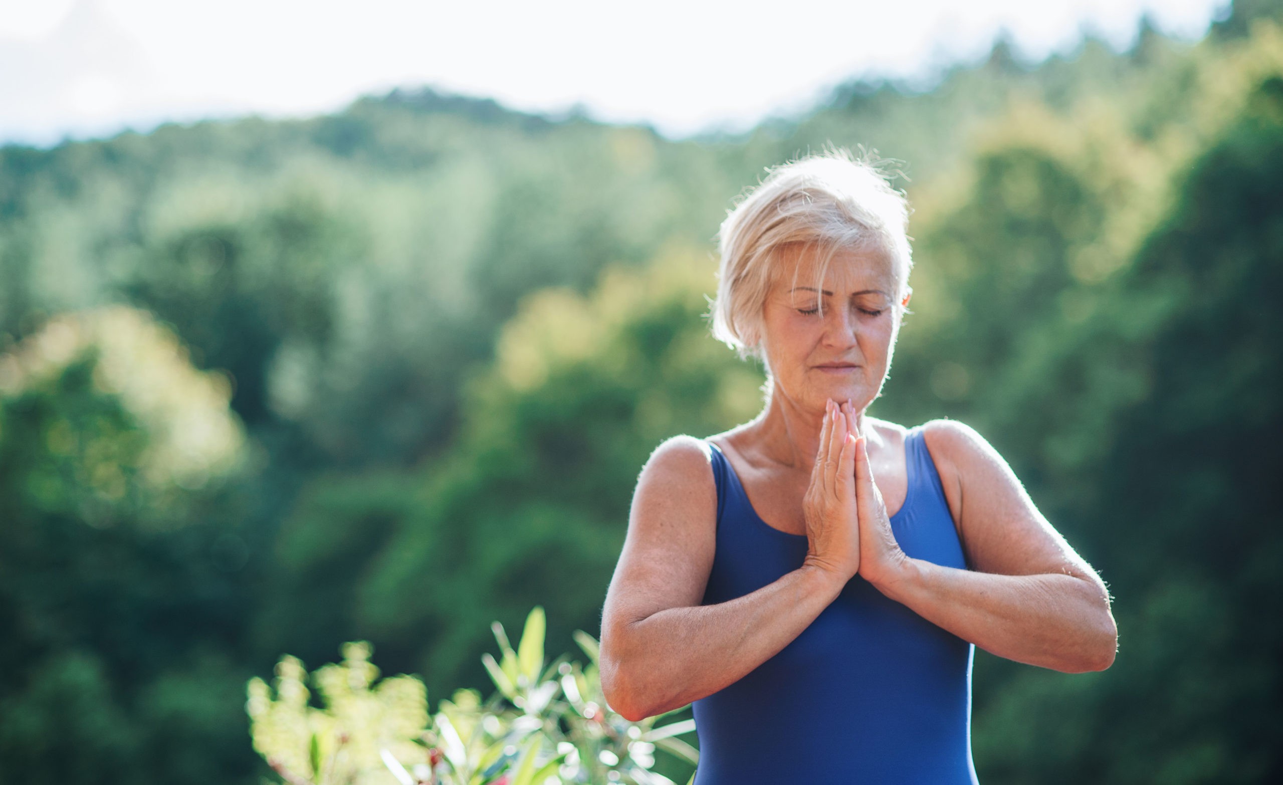 Ältere Frau meditiert in der Natur