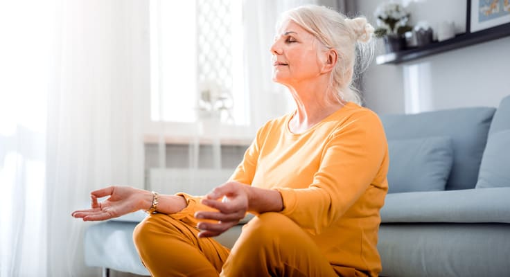 Aeltere Frau meditiert sitzend