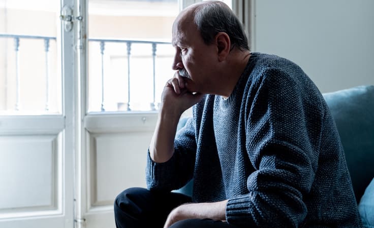 Aelterer Mann schaut traurig aus dem Fenster