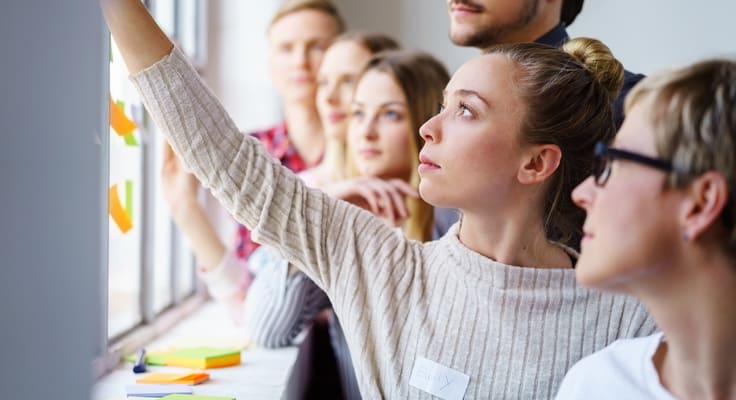 Frau zeigt Gruppenteilnehmern etwas auf Post-its